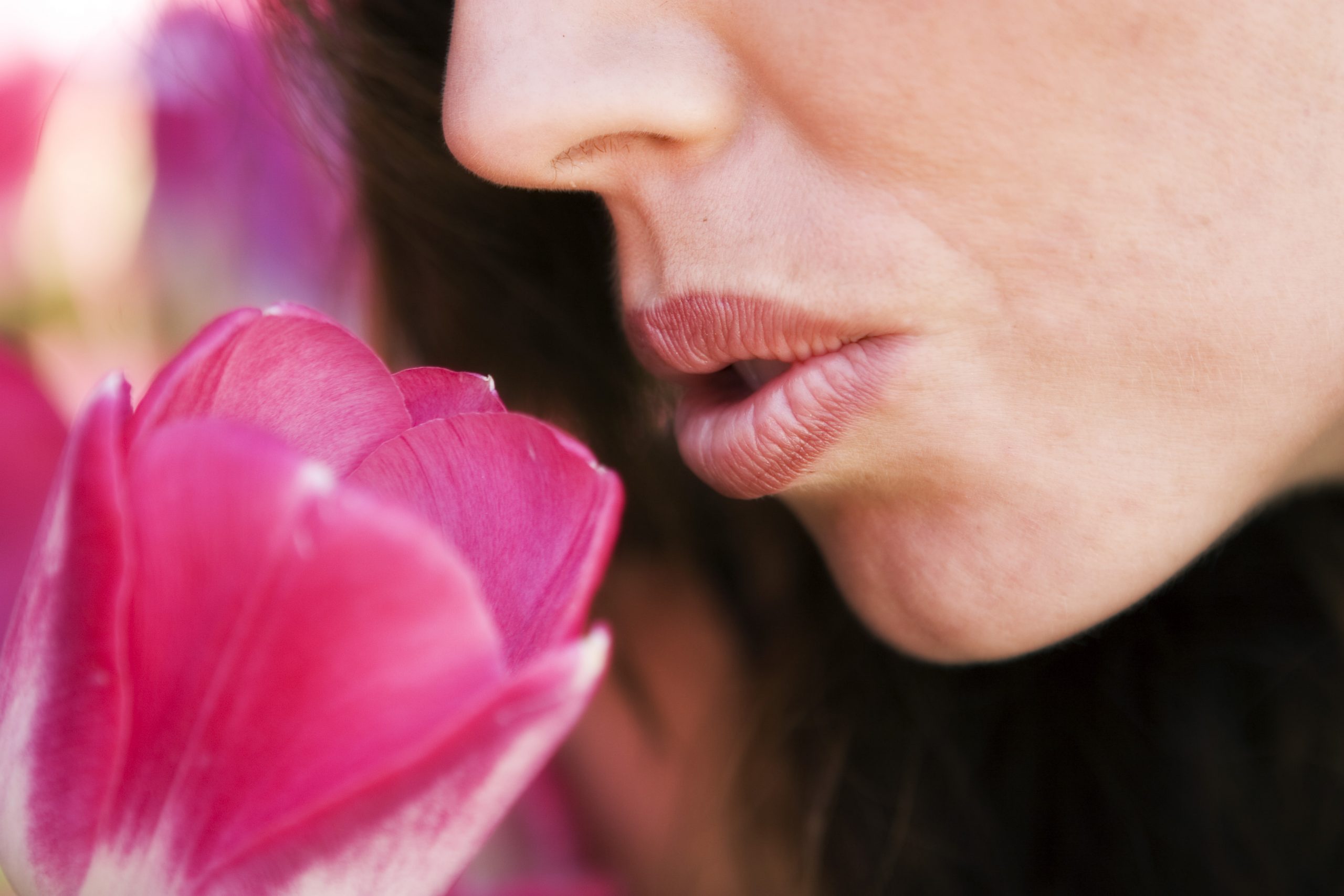 A woman is smelling a pink flower, promoting optimal health.