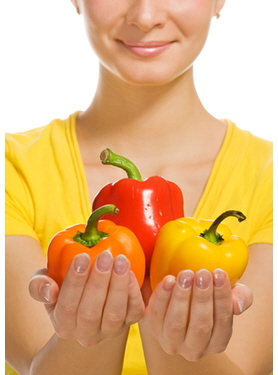 A woman holding three stuffed bell peppers in her hands.