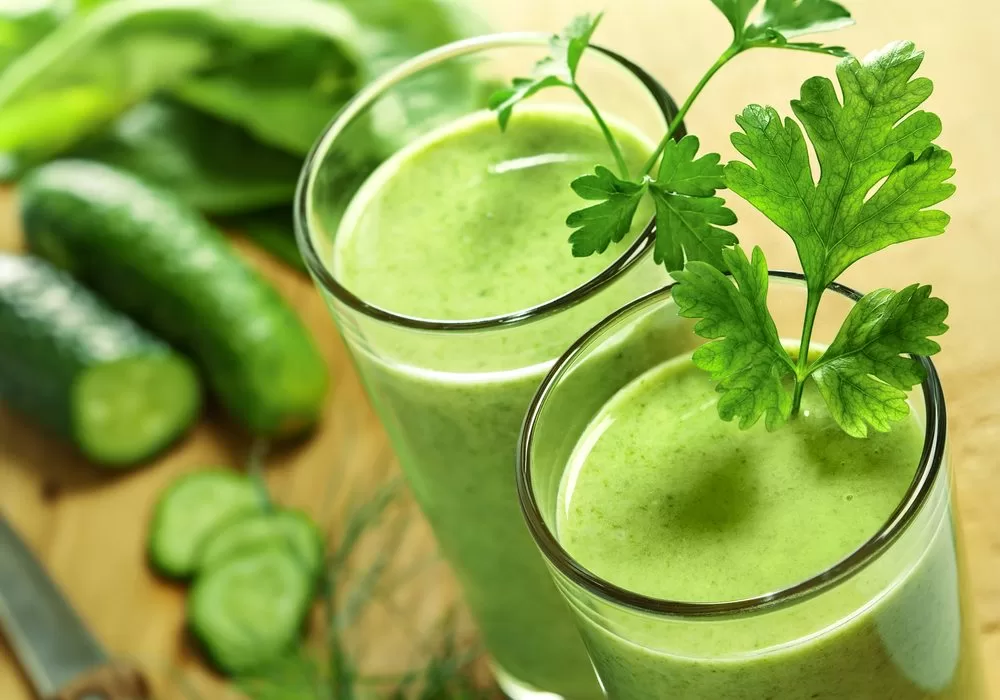 Two glasses of green smoothie with cucumbers and parsley that promote optimal health.