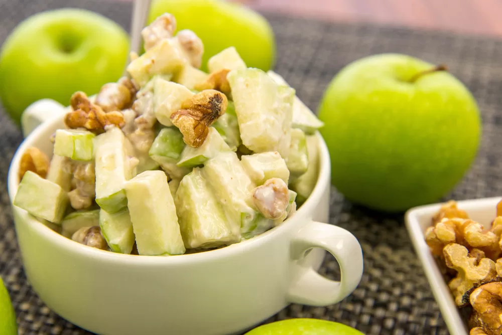 Functional nutrition is promoted by serving an apple salad with walnuts in a bowl.