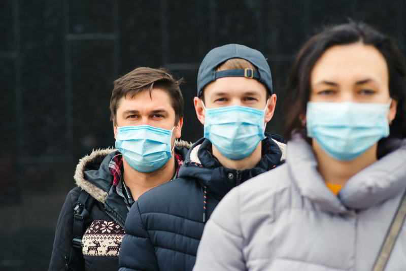 A group of people wearing surgical masks, some suffering from Long-Hauler Syndrome.
