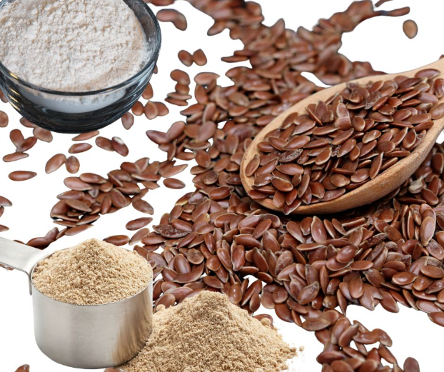 A wooden spoon and scattered flaxseeds with a metal scoop of ground flaxseed and a glass bowl of flour, all displayed on a white background.